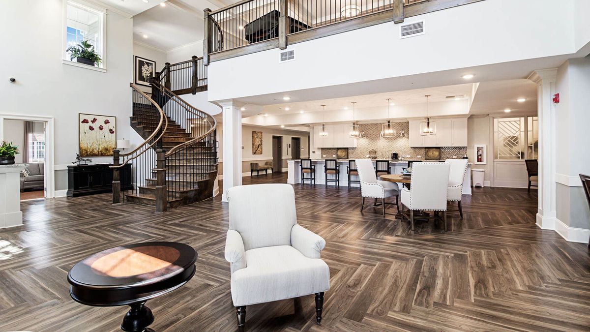 A spacious and modern open-concept living area with a view of the kitchen and an elegant staircase.