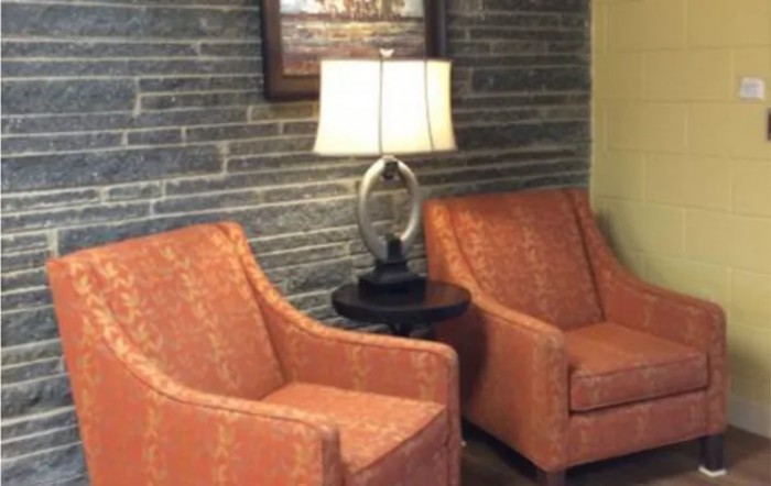 A cozy seating area with two armchairs, a lamp, and decorative wall art.