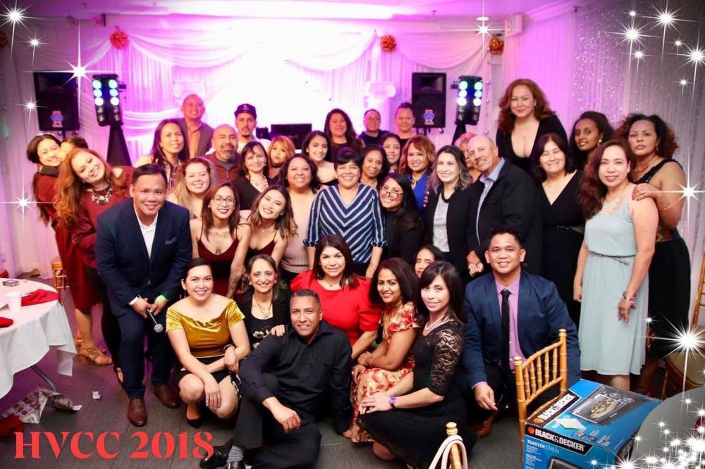 A large group of people gathered for a celebration, dressed in formal attire, smiling and posing together in an indoor setting.