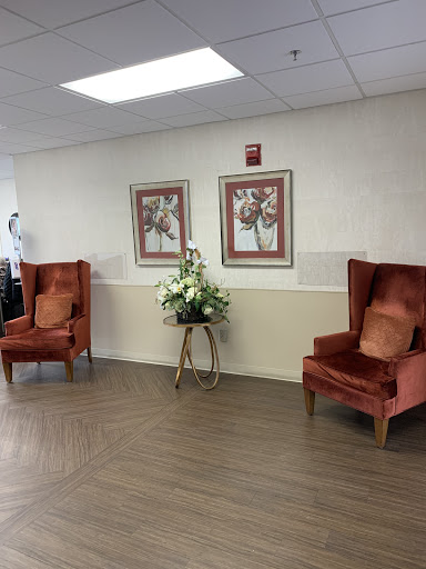A cozy waiting area featuring two orange armchairs and decorative artwork on the walls.