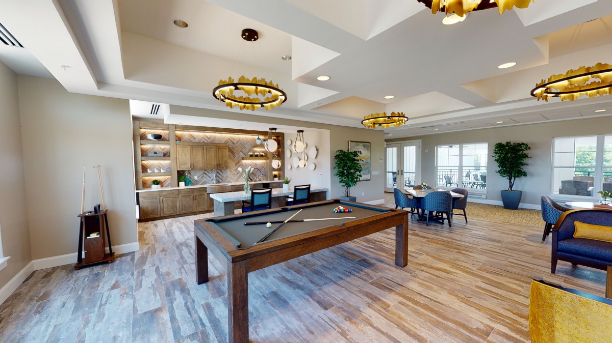A modern game room featuring a pool table, seating area, and stylish lighting.