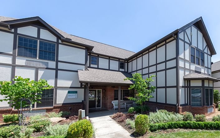 A two-story residential building with a Tudor-style exterior and landscaped front yard.