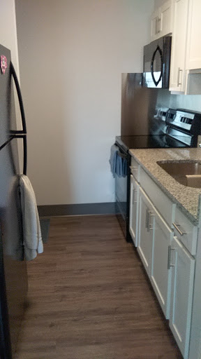 A modern kitchen featuring essential appliances, granite countertops, and wooden flooring.