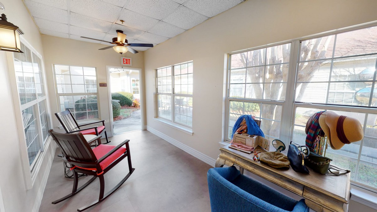 A cozy sunroom with ample natural light, featuring a rocking chair and an armchair for relaxation.
