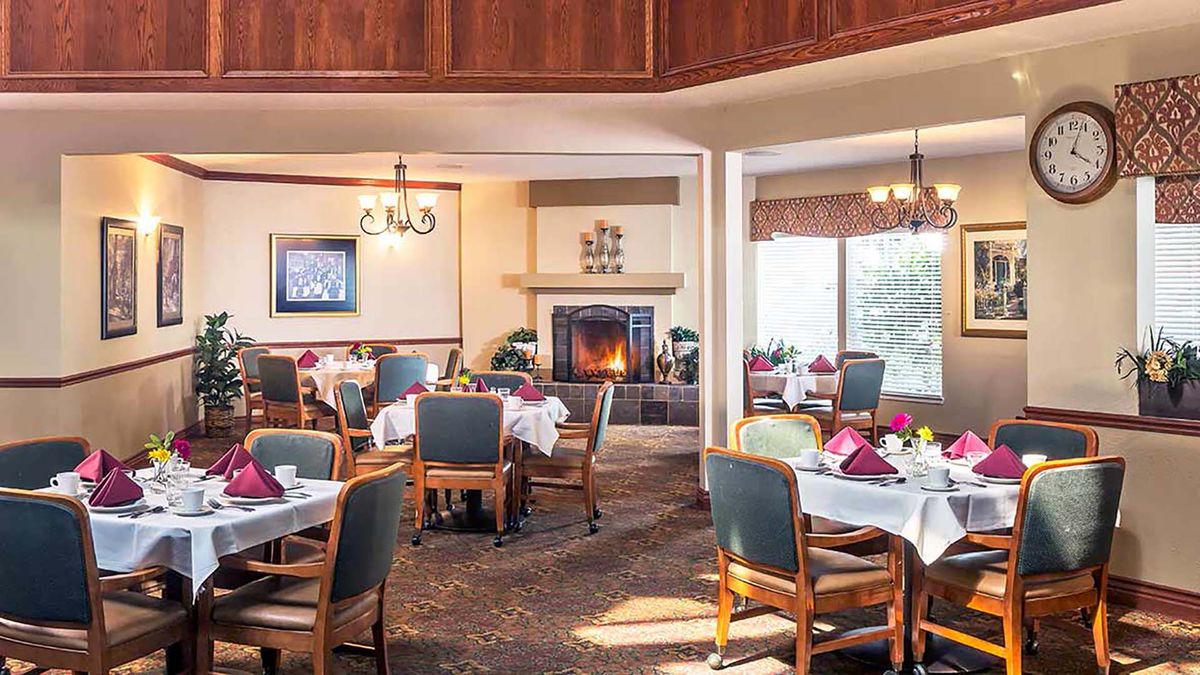 A cozy restaurant dining area featuring neatly set tables and a warm fireplace.