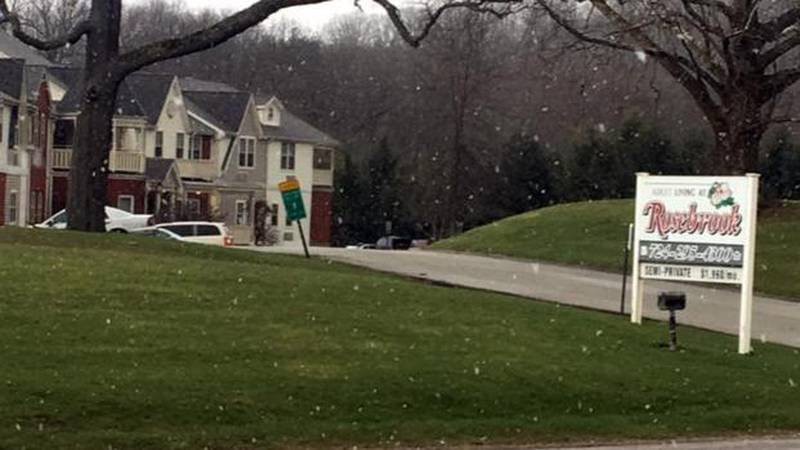 A suburban house with snow falling on a winter day.