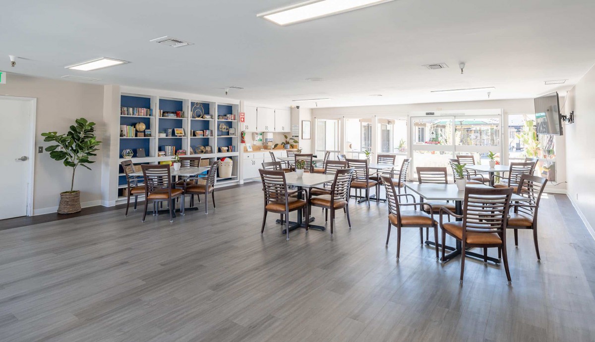 A bright and spacious dining area with tables, chairs, and bookshelves lining the walls.