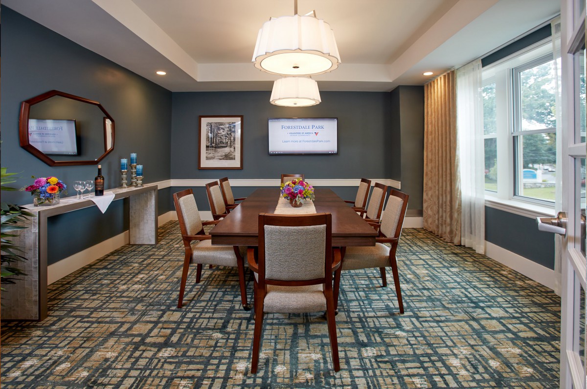 A well-lit meeting room with a large conference table and chairs, featuring decorative lighting and carpet.