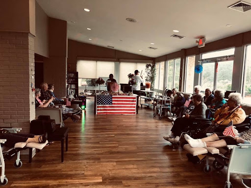 A gathering of people in a spacious indoor area with an American flag displayed prominently.