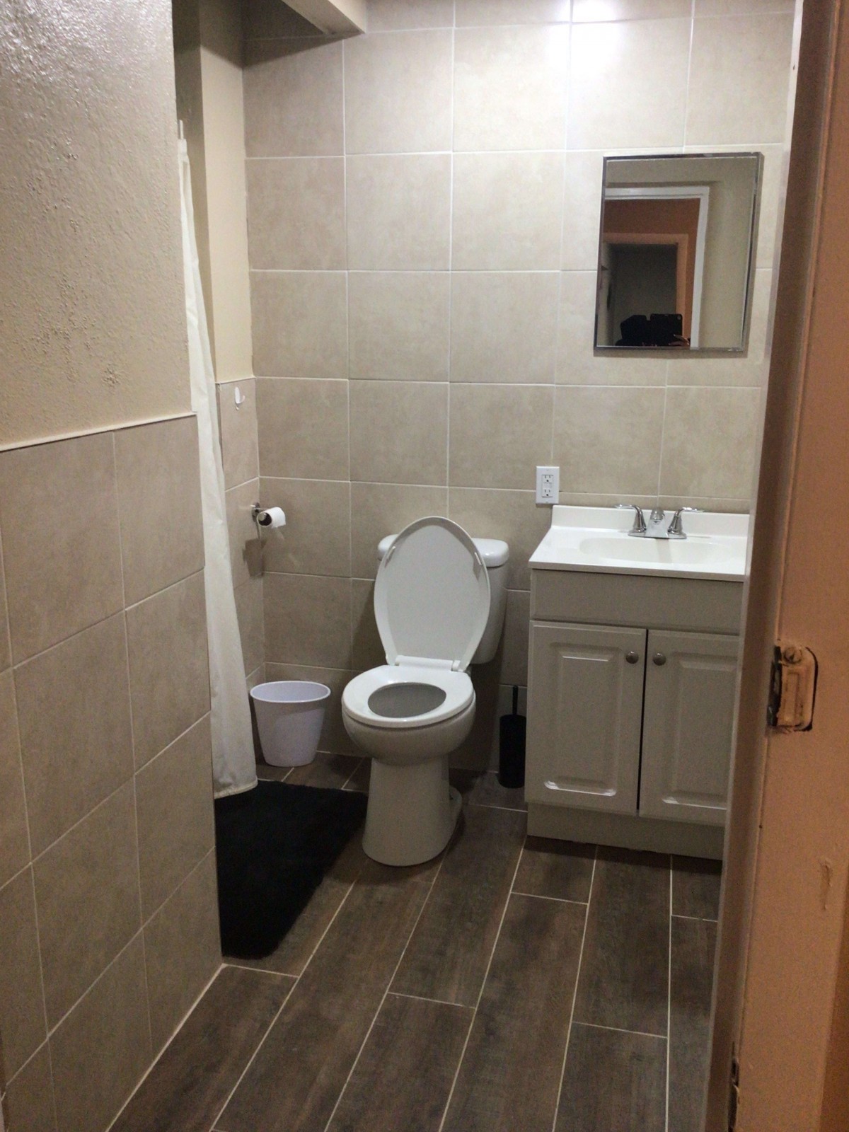 A simple bathroom with a toilet, sink, and mirror.