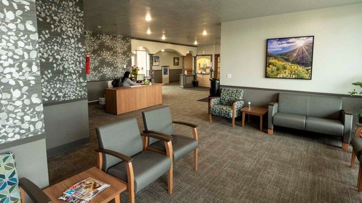 A spacious waiting room with comfortable seating and a reception desk, adorned with decorative artwork.