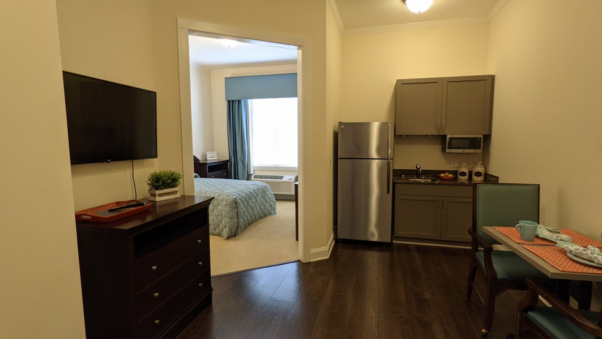 A modern apartment interior featuring a small kitchen area and adjacent bedroom.