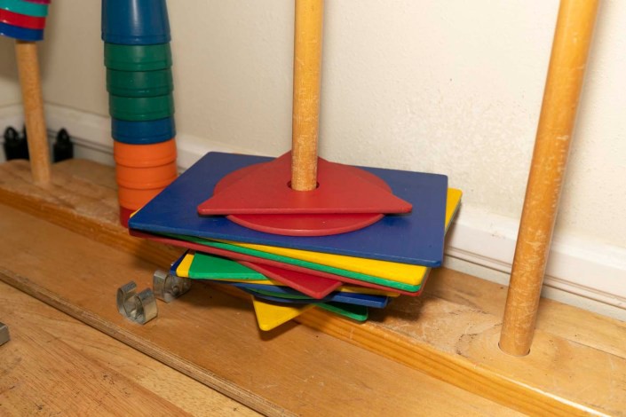 A colorful stacking toy with various geometric shapes on a wooden base.