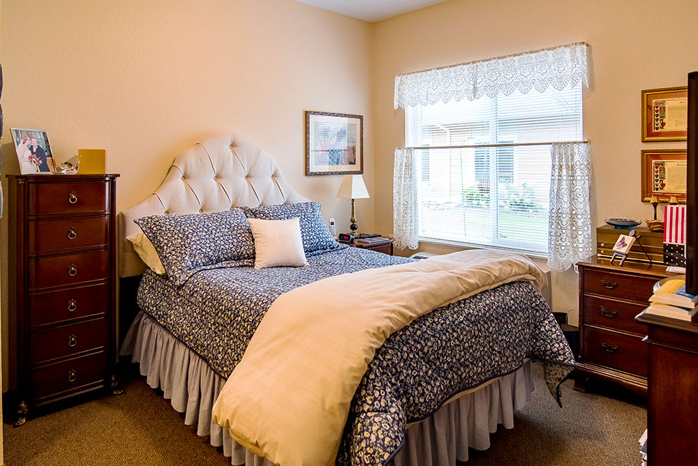 A cozy bedroom with a bed, natural lighting, and decorative elements.