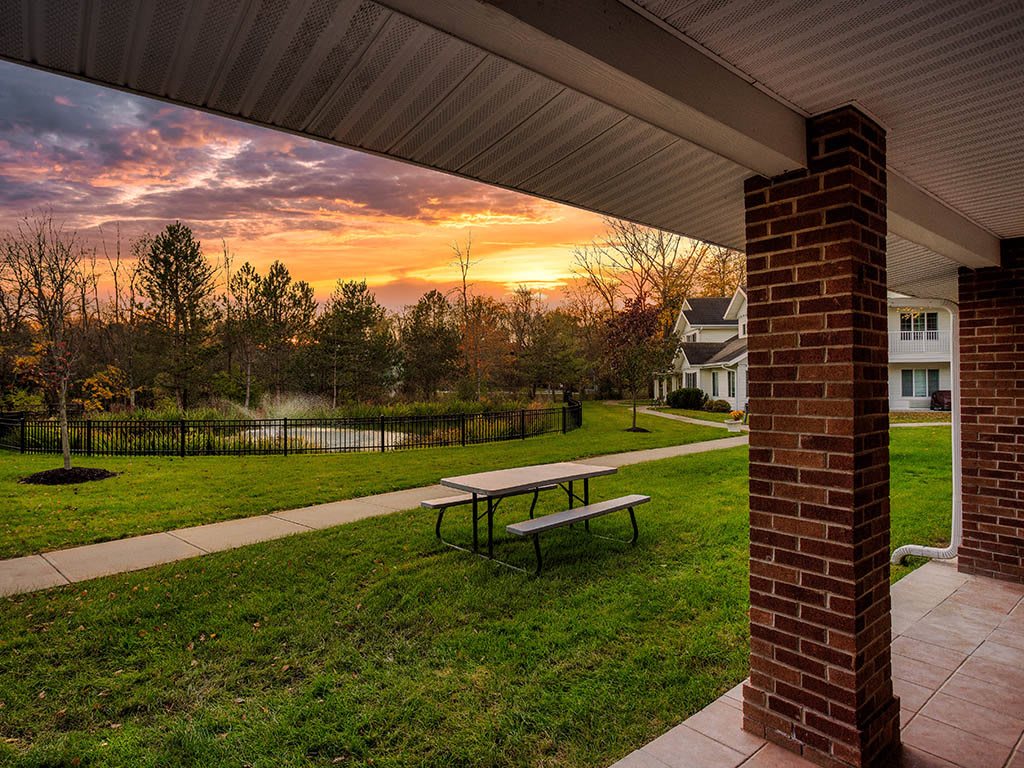 A picturesque sunset over a serene park with a bench and pathway.