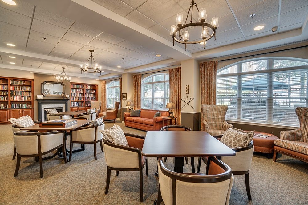 A cozy living room with seating areas, chandeliers, and large windows.