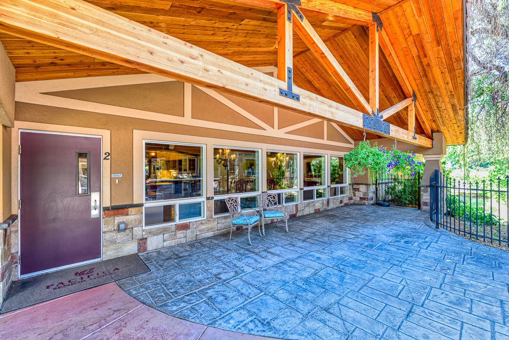 A welcoming building entrance with wooden beams and outdoor seating.