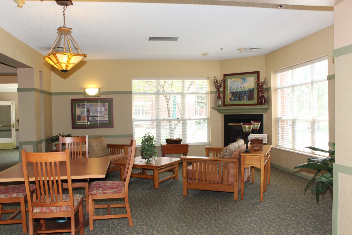 A cozy living room area with wooden furniture, a fireplace, and large windows.