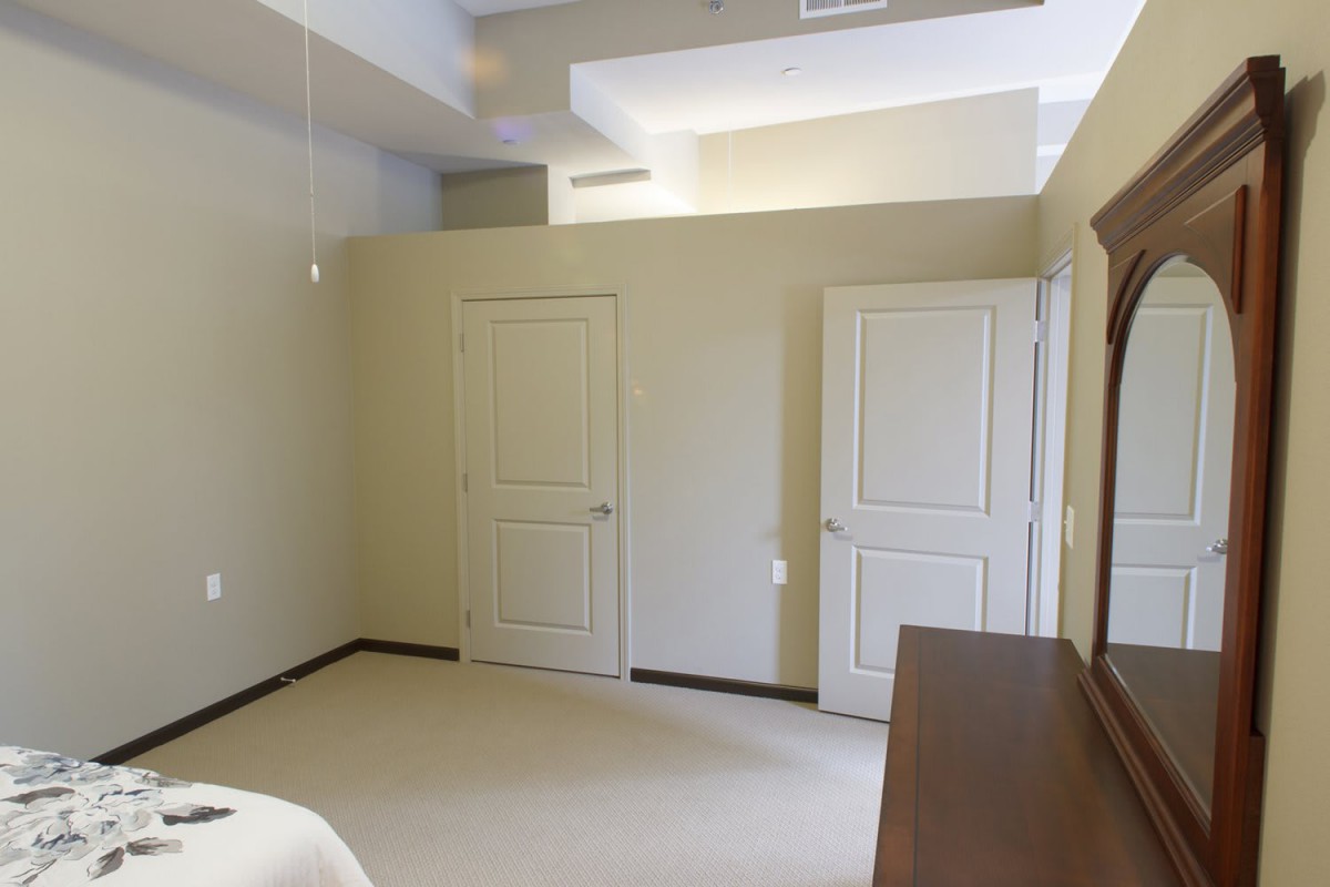 A minimalist bedroom with two doors and a ceiling fan.