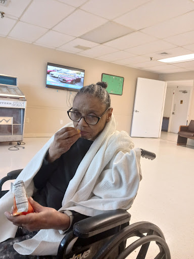 A person in a wheelchair enjoying a snack in a healthcare facility.