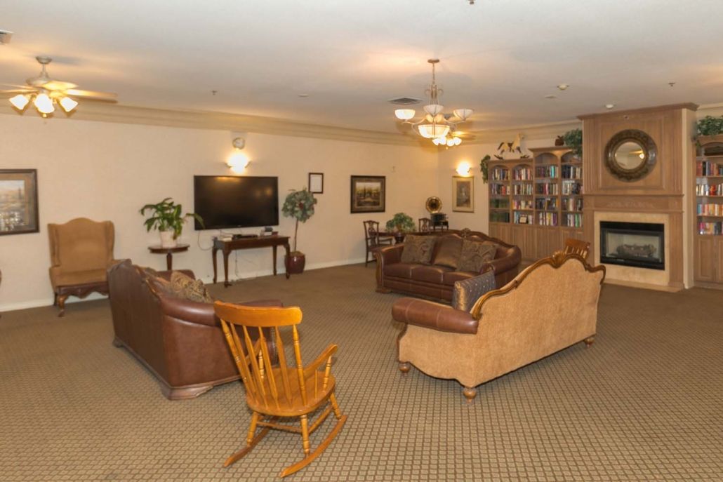 A cozy living room with sofas, a rocking chair, a television, and a bookshelf.