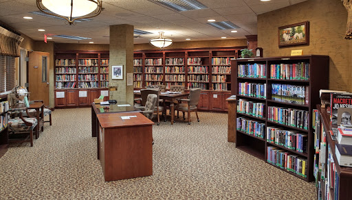 A cozy library with wooden shelves filled with books and a dedicated reading area.