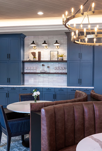 A stylish and modern kitchen featuring blue cabinetry, elegant lighting, and a cozy dining area.