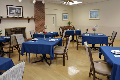 A cozy dining area featuring blue tablecloths and comfortable chairs, set for a meal.