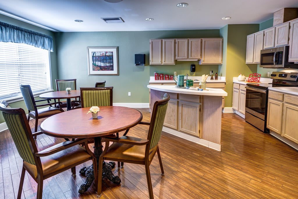 A cozy dining area with round tables and a small kitchen setup.