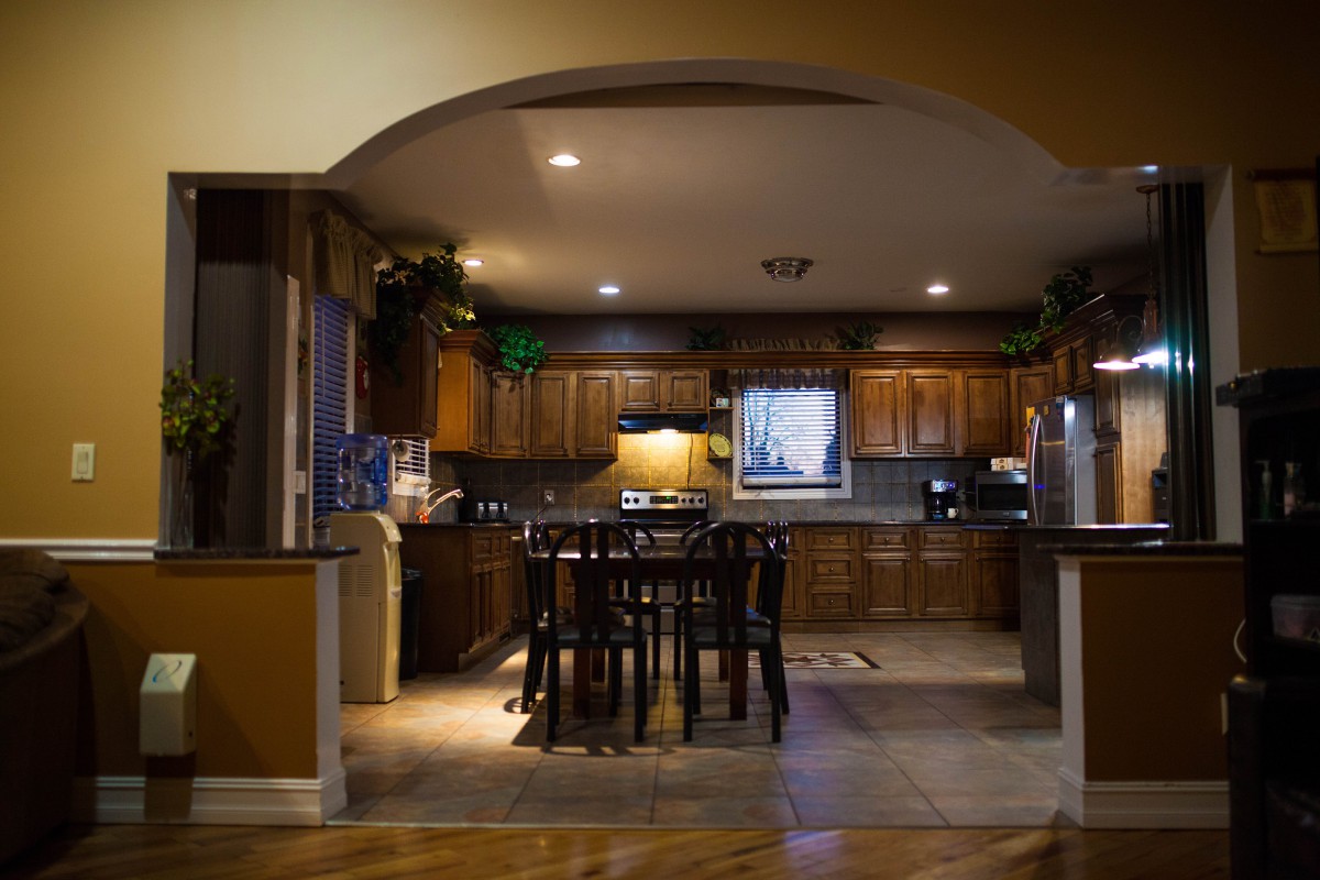 A cozy kitchen with wooden cabinets and a dining area under warm lighting.