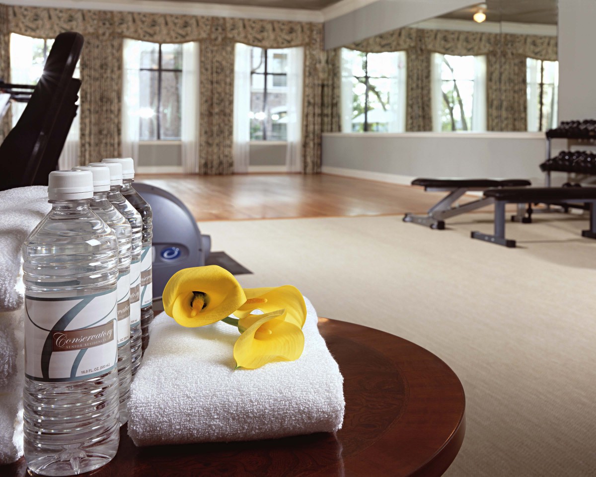 A well-equipped gym with towels, dumbbells, and water bottles ready for use.