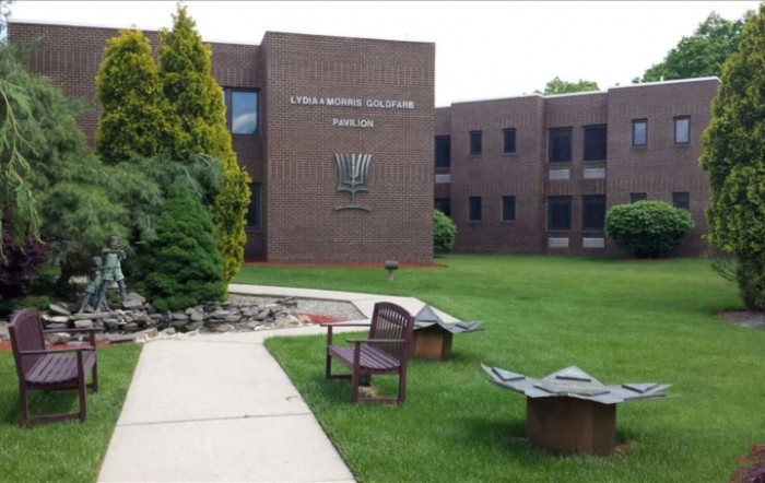 A brick office building with a landscaped lawn and benches.