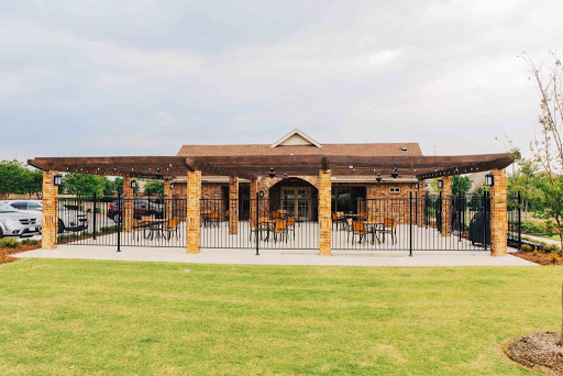 A charming outdoor restaurant with a spacious patio and a well-maintained grassy area.