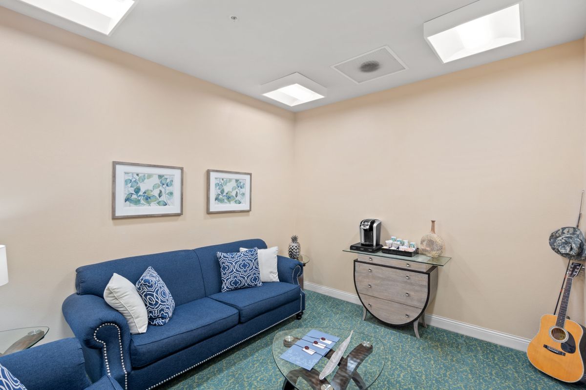 A cozy waiting room with a blue sofa and a coffee station.