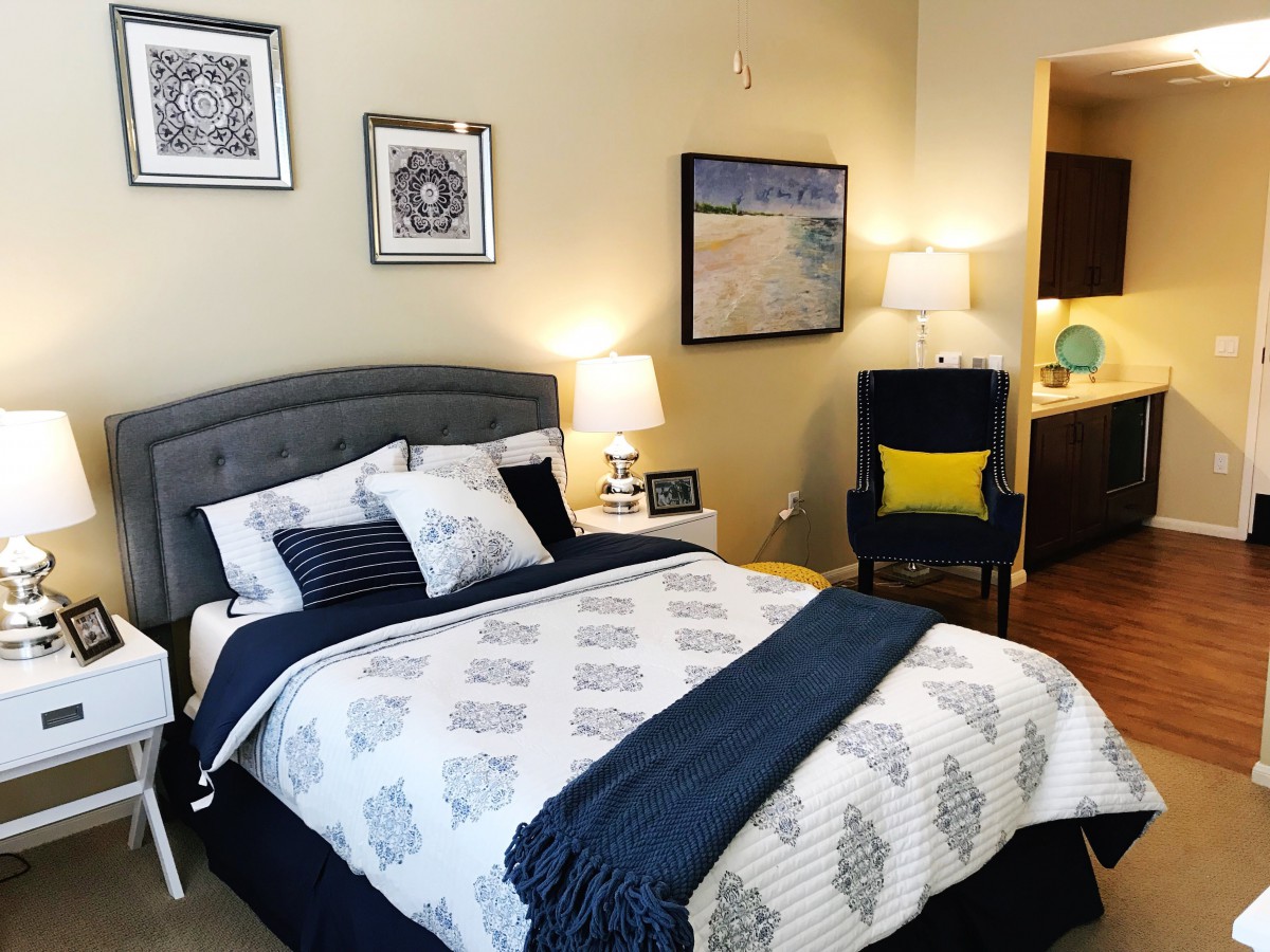 A cozy bedroom with stylish decor, featuring a neatly made bed, decorative pillows, and complementary artwork on the walls.