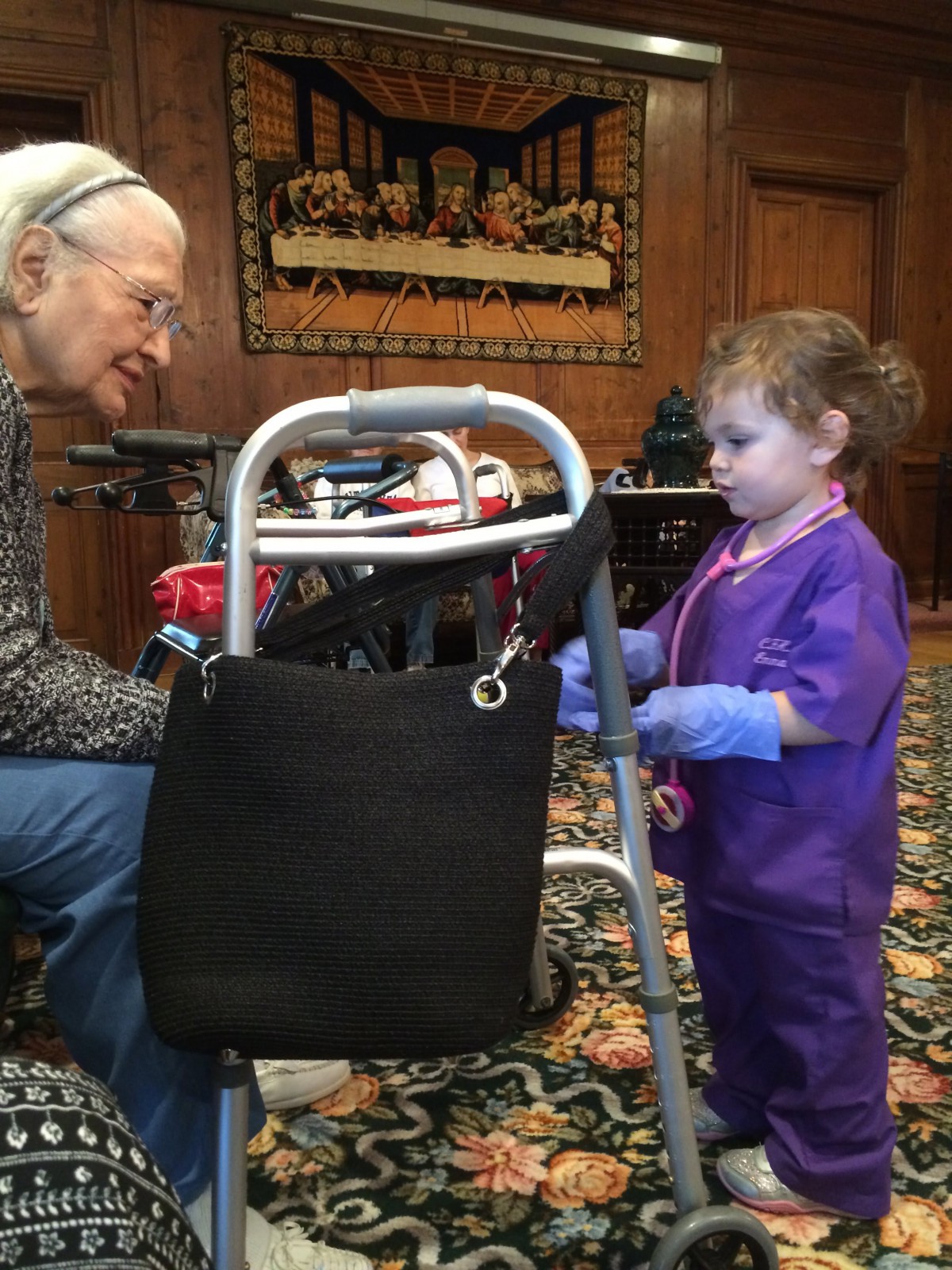 A child in purple attire interacts with an elderly person using a walker.
