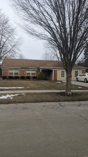 A cozy suburban house during winter, featuring a neatly trimmed lawn and a bare tree.