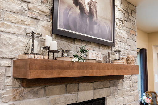 A beautifully styled fireplace mantel featuring a stone wall, decorative candles, and an elegant horse painting.