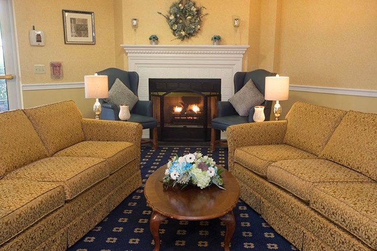 A cozy living room with a fireplace, two sofas, armchairs, and a decorated coffee table.