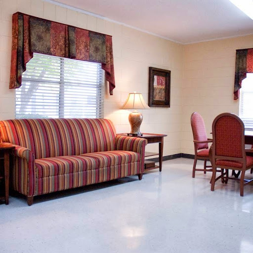 A cozy living space featuring a striped sofa, a dining area with wooden chairs, and soft lighting.