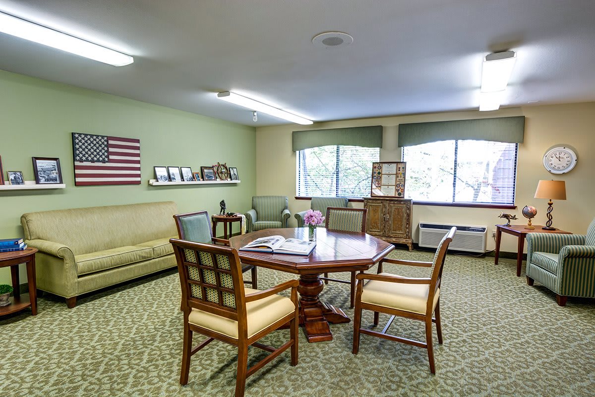 An office meeting room with a round table, chairs, and an American flag on the wall.