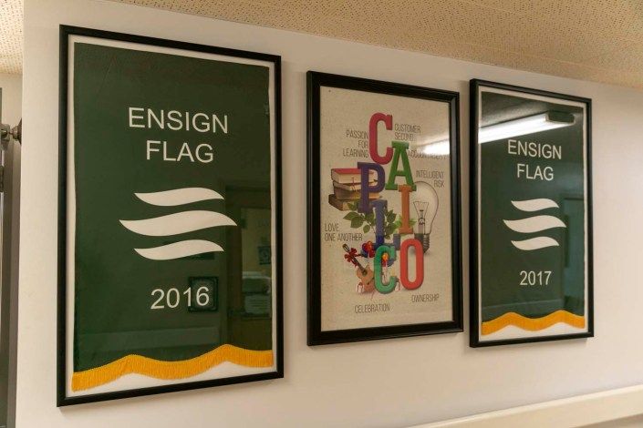 A wall displaying framed posters featuring 'Ensign Flag' and 'Calico' artwork from 2015.