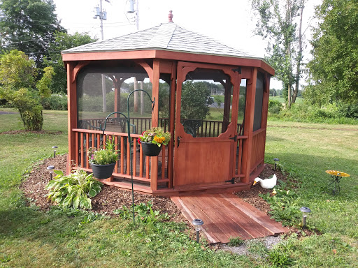 A charming wooden gazebo surrounded by lush greenery and decorative plants, creating a serene outdoor space.