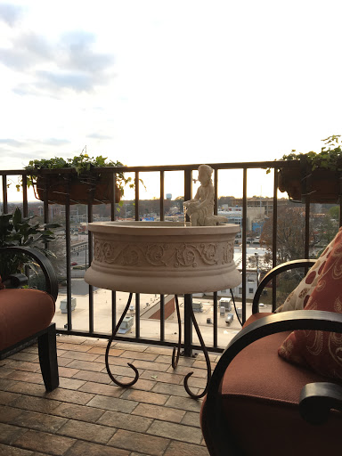 A cozy balcony setting with comfortable seating, planters, and a beautiful city view during sunset.