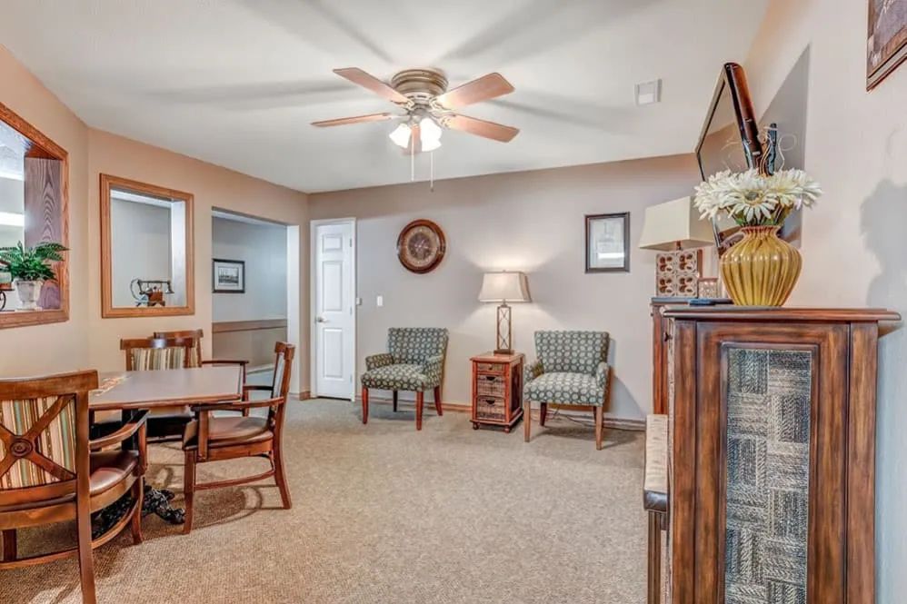 A cozy living room with comfortable seating, a ceiling fan, and warm lighting.