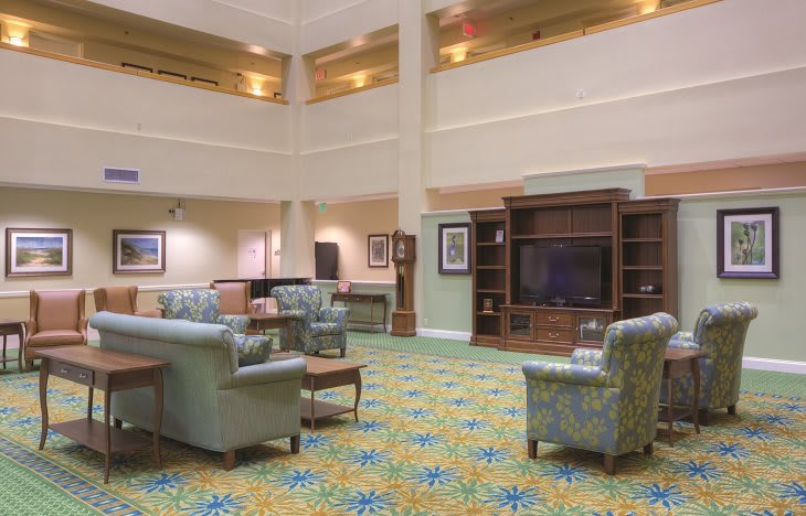 Spacious hotel lobby with comfortable seating and a large television.