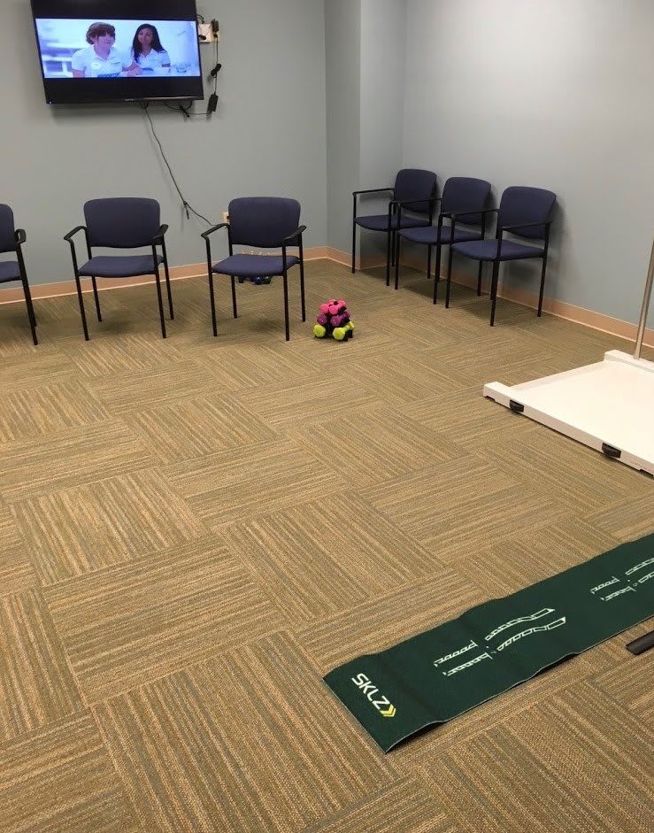 A meeting room equipped with chairs, a television, and a putting mat on the floor.