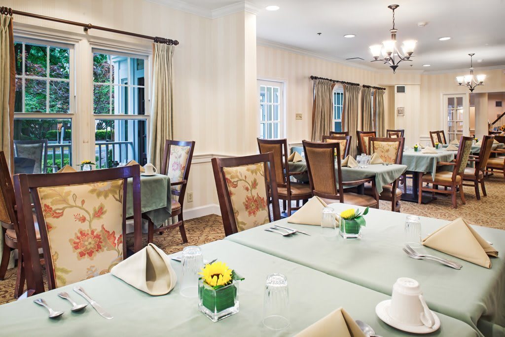 A cozy dining room setup with arranged tables and chairs, decorated with floral accents.