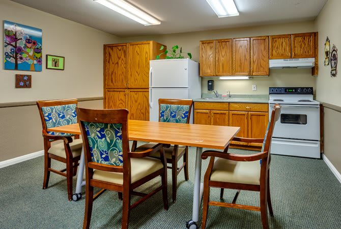 A cozy kitchen and dining area with wooden cabinets, a table, and chairs.