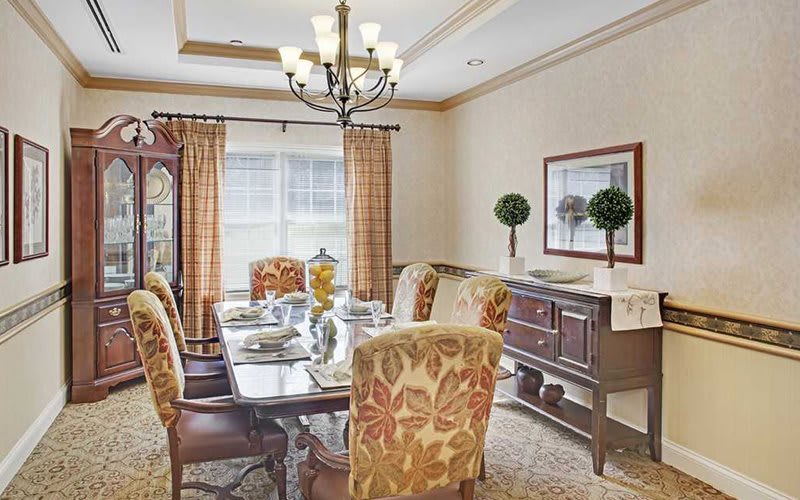 A well-decorated dining room with a chandelier, set table, and elegant furnishings.